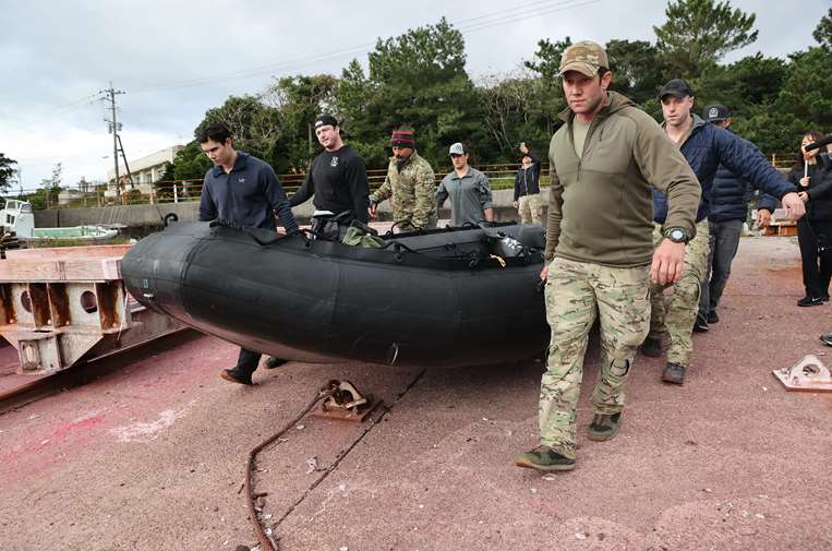 Personal militar estadounidense lleva un bote para el rescate / Foto: AFP