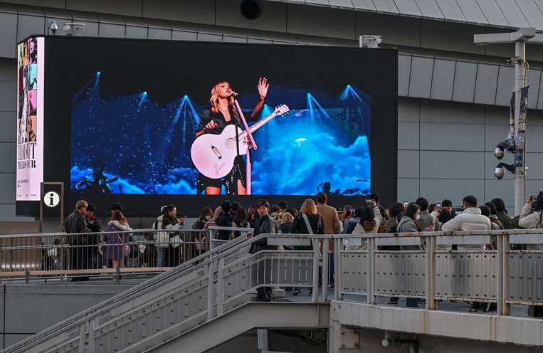 Seguidores de Taylor Swift miran los videos de los shows de la cantante en Tokio / AFP