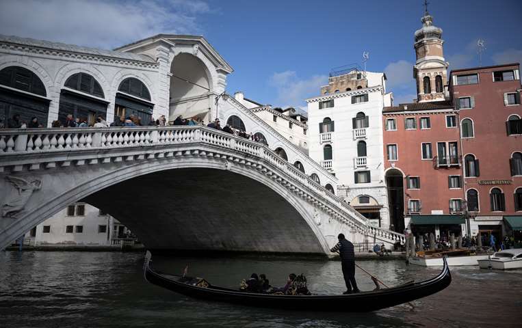 Una góndola pasa bajo el Puente de Rialto en Venecia / AFP